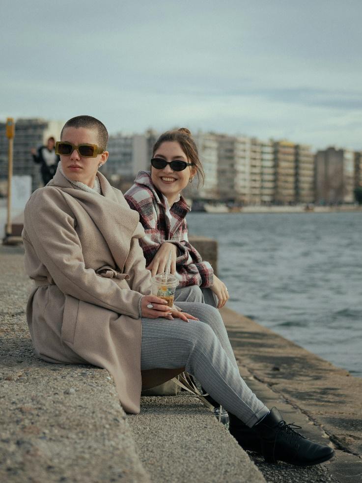 a man and a woman sitting on a pier next to a body of water