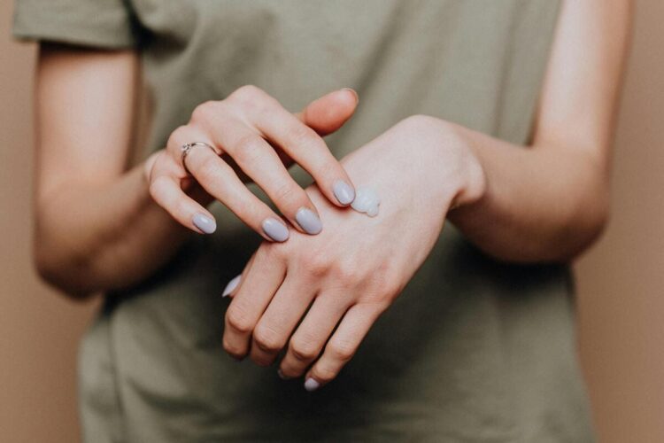 Crop woman applying cream on hands