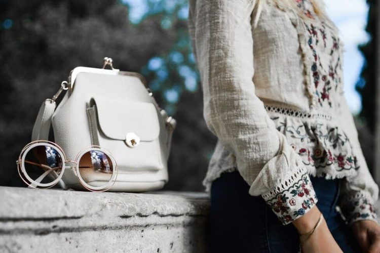 Fashion influencer sitting with the purse with glasses on it