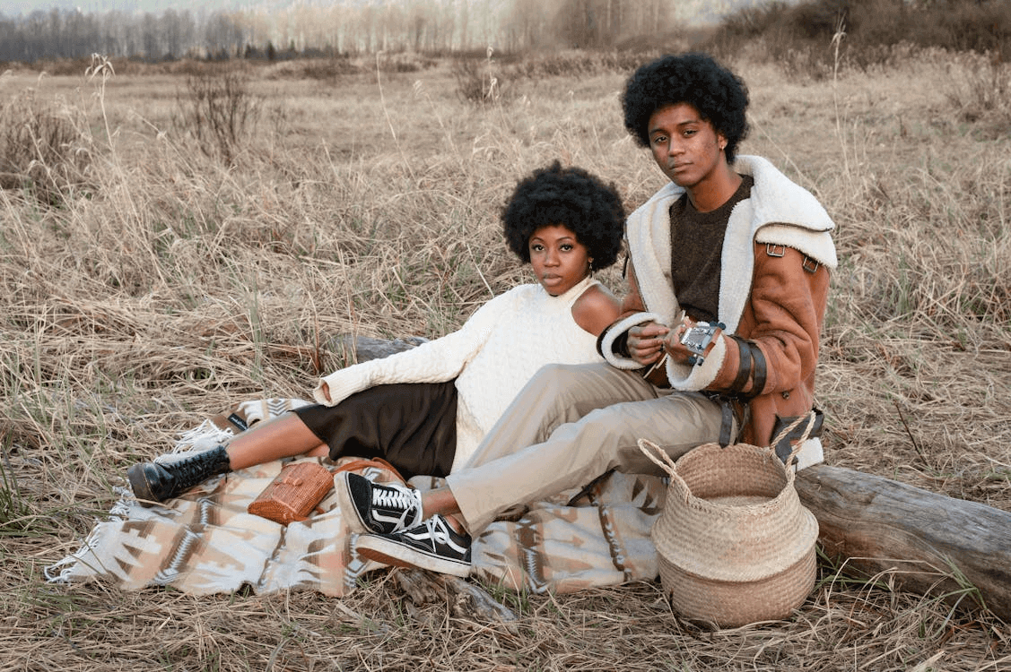 Man and woman sitting on a blanket in a field with vintage style