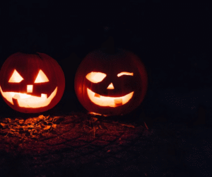 Two carved pumpkins illuminated in the dark