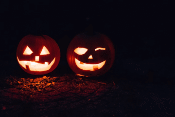 Two carved pumpkins illuminated in the dark