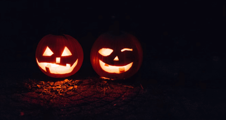 Two carved pumpkins illuminated in the dark