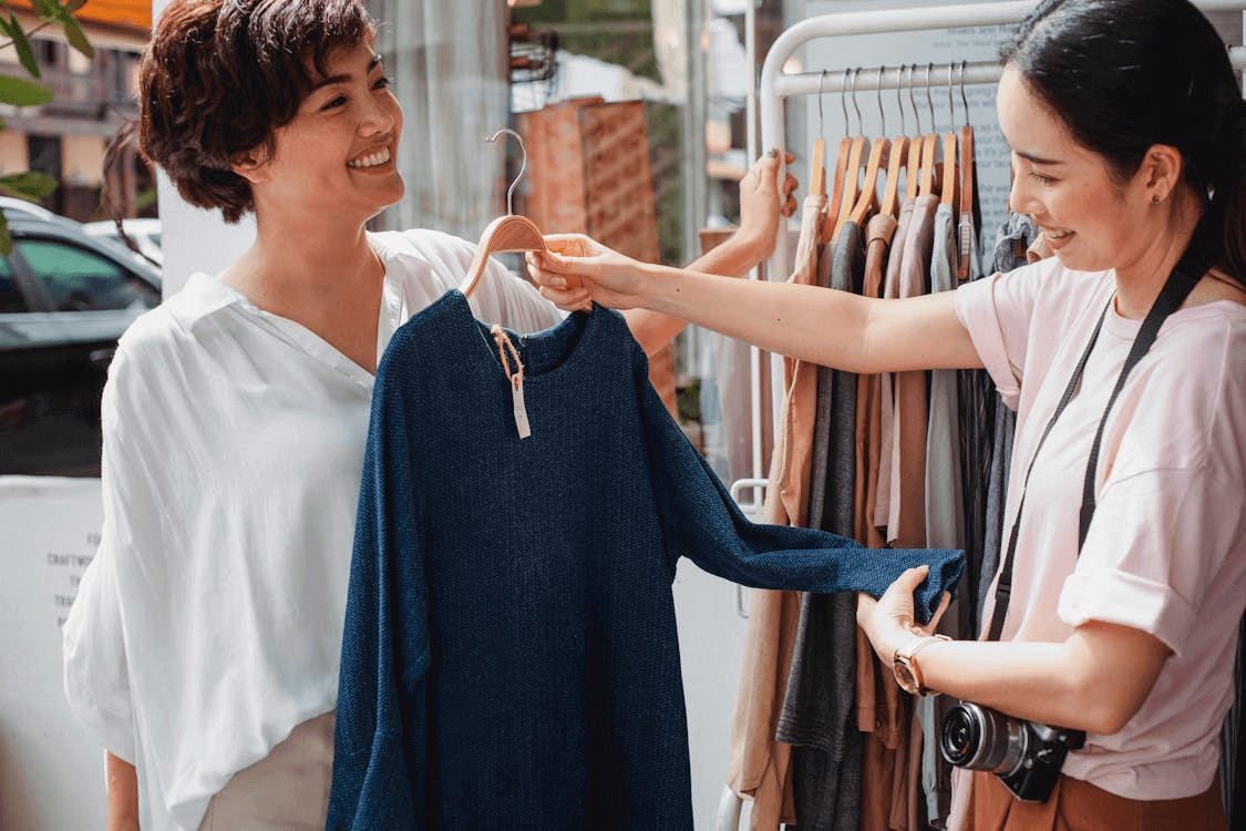 Two women examining clothing rack for business investment ideas