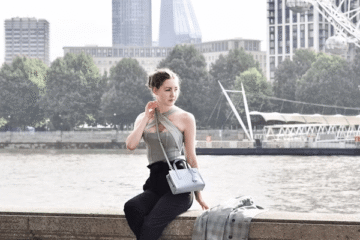 Woman sitting by water in stylish London outfit
