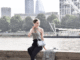 Woman sitting by water in stylish London outfit