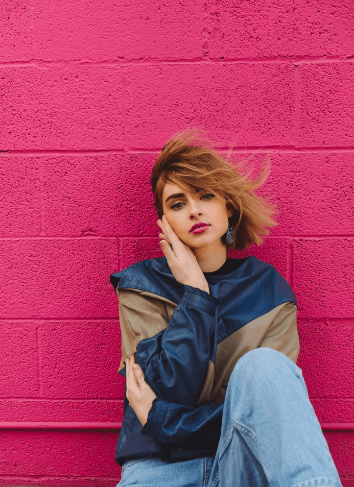 Woman sitting on ground near pink wall showcasing personal style transformation