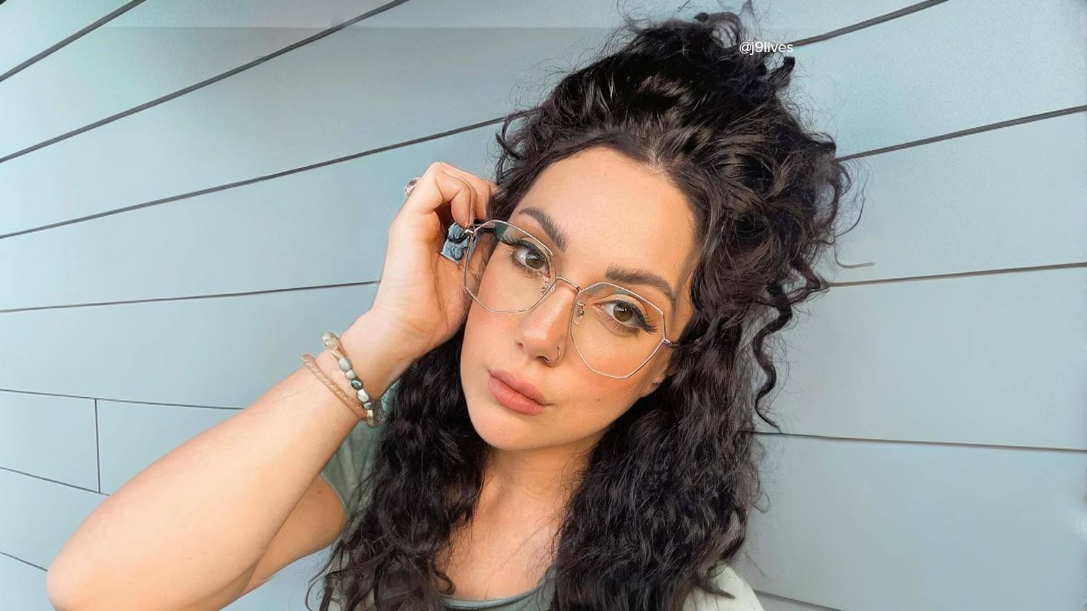 Woman with glasses leaning against wall